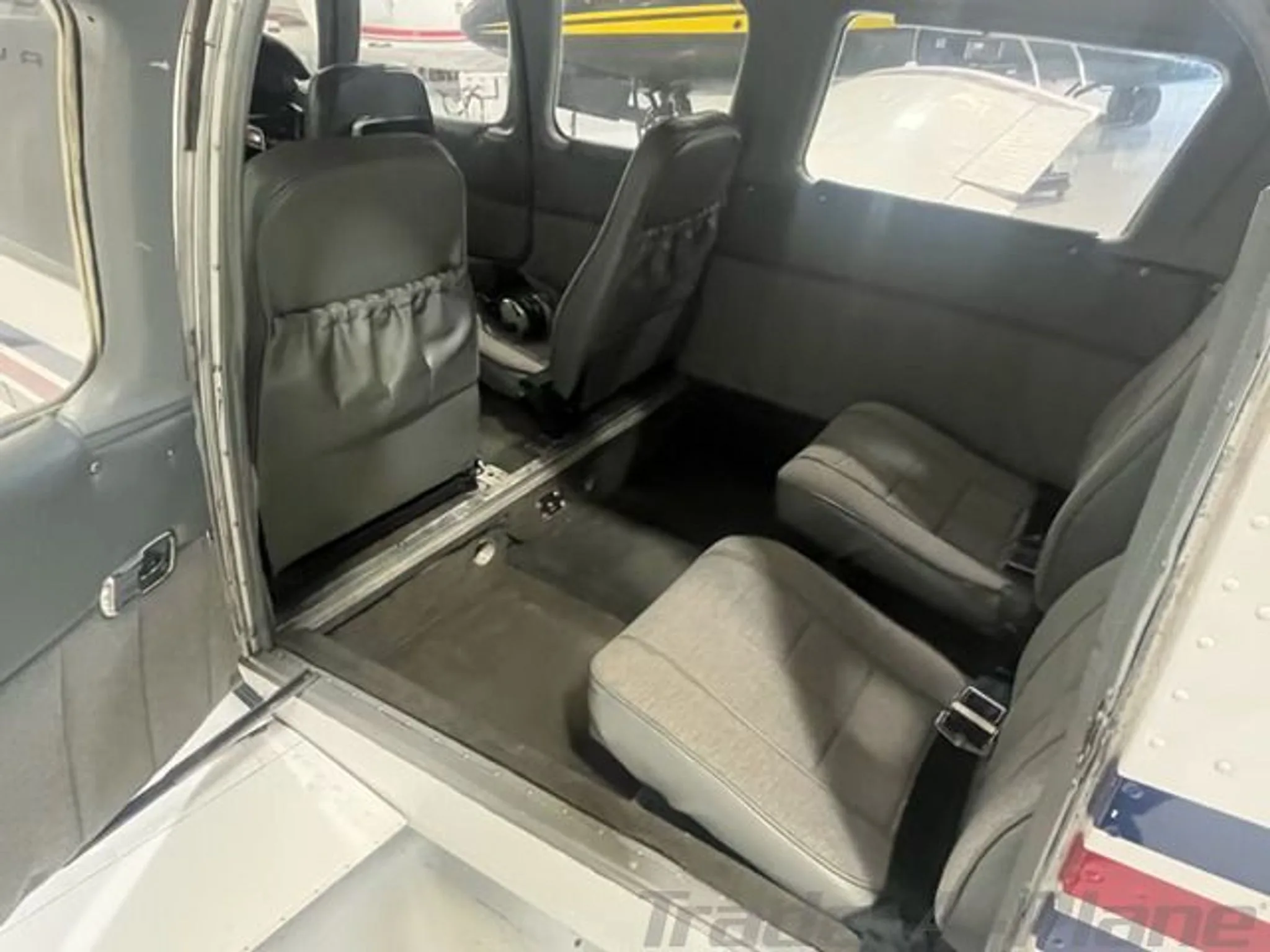 The aircraft's gray interior cabin features four seats, with the door open.
