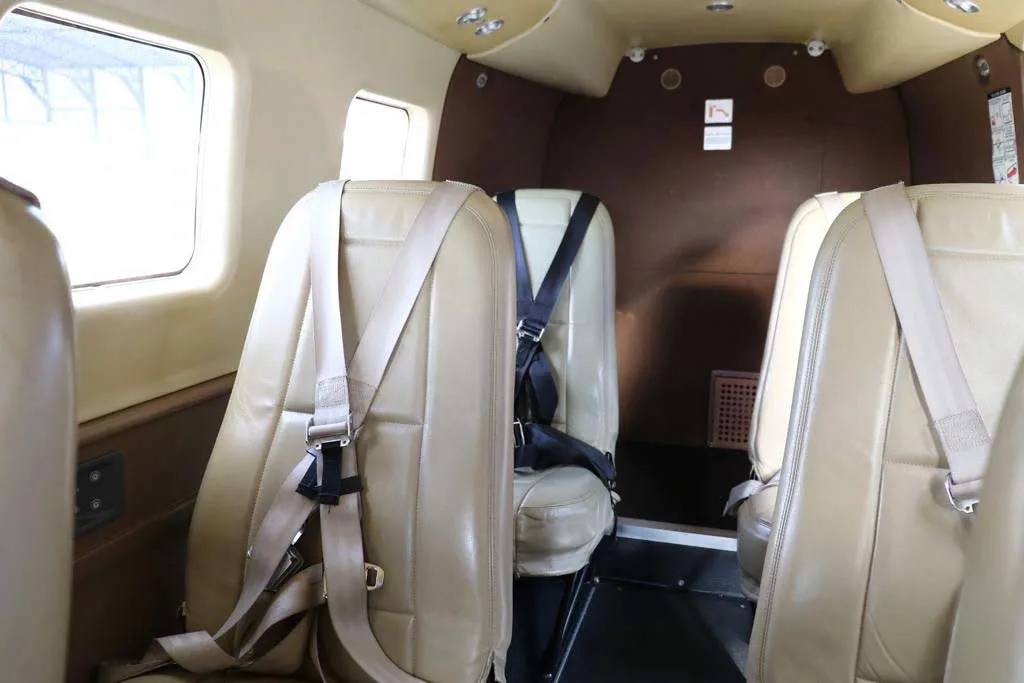 A close-up view of light tan passenger seats with harnesses in an aircraft cabin.