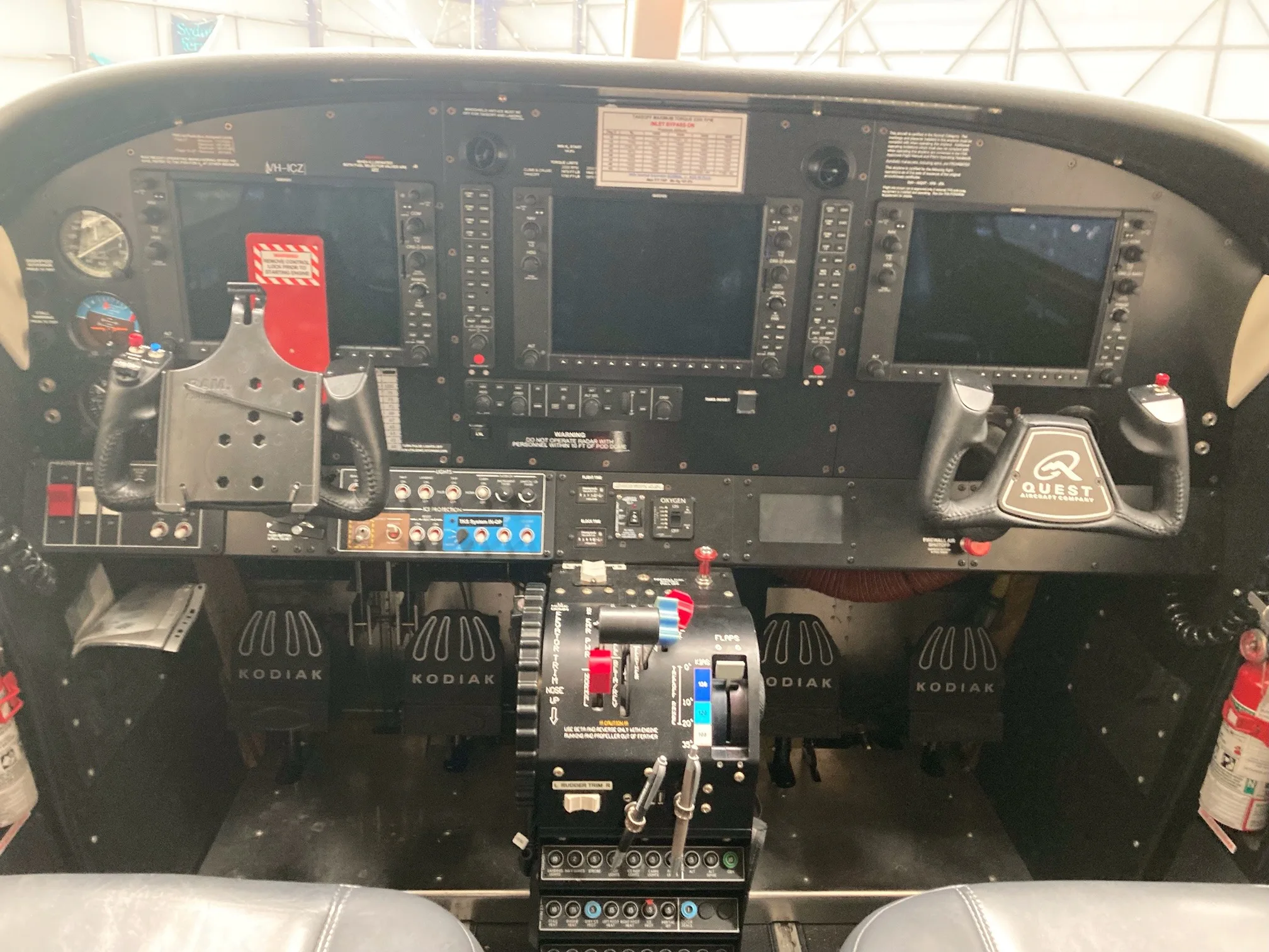 The cockpit of a Quest Kodiak 100 aircraft, showing the instrument panel with two large screens, yokes, and central throttle quadrant.