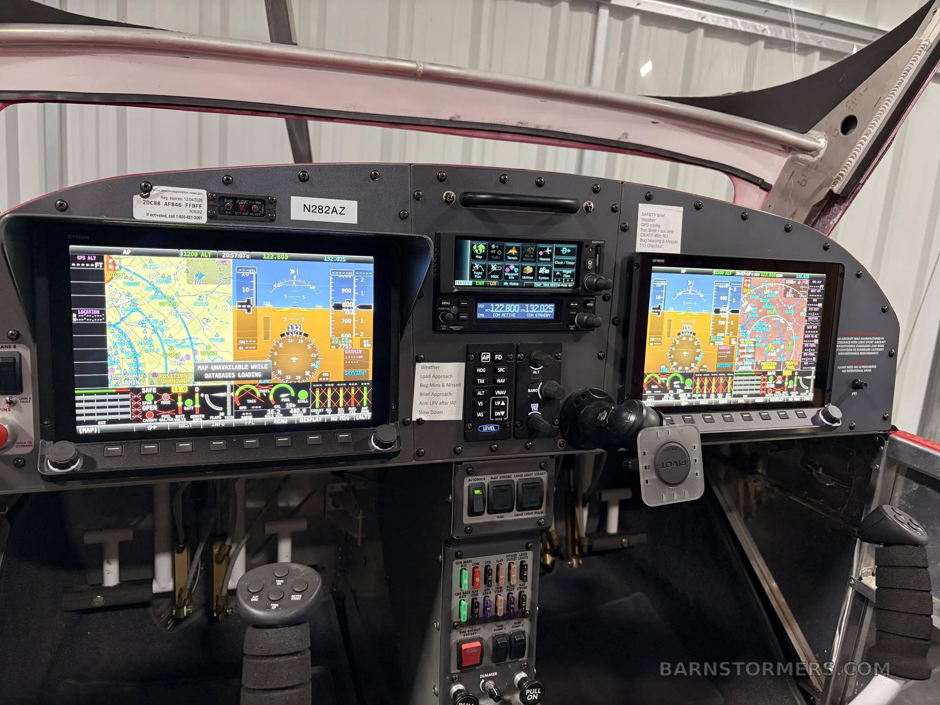 The cockpit of a red and grey aircraft, featuring two large digital display screens and various control panels.