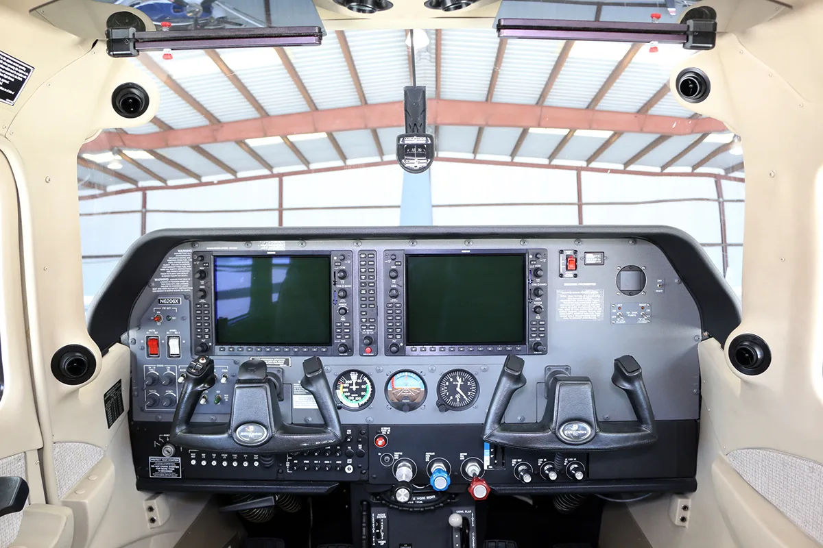 The cockpit of the aircraft, featuring a modern glass panel with two large displays and dual yokes.