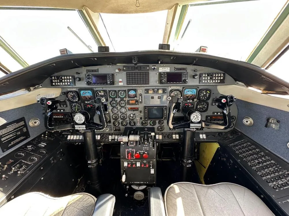 The cockpit of an aircraft, showing the instrument panel, yokes, and controls.