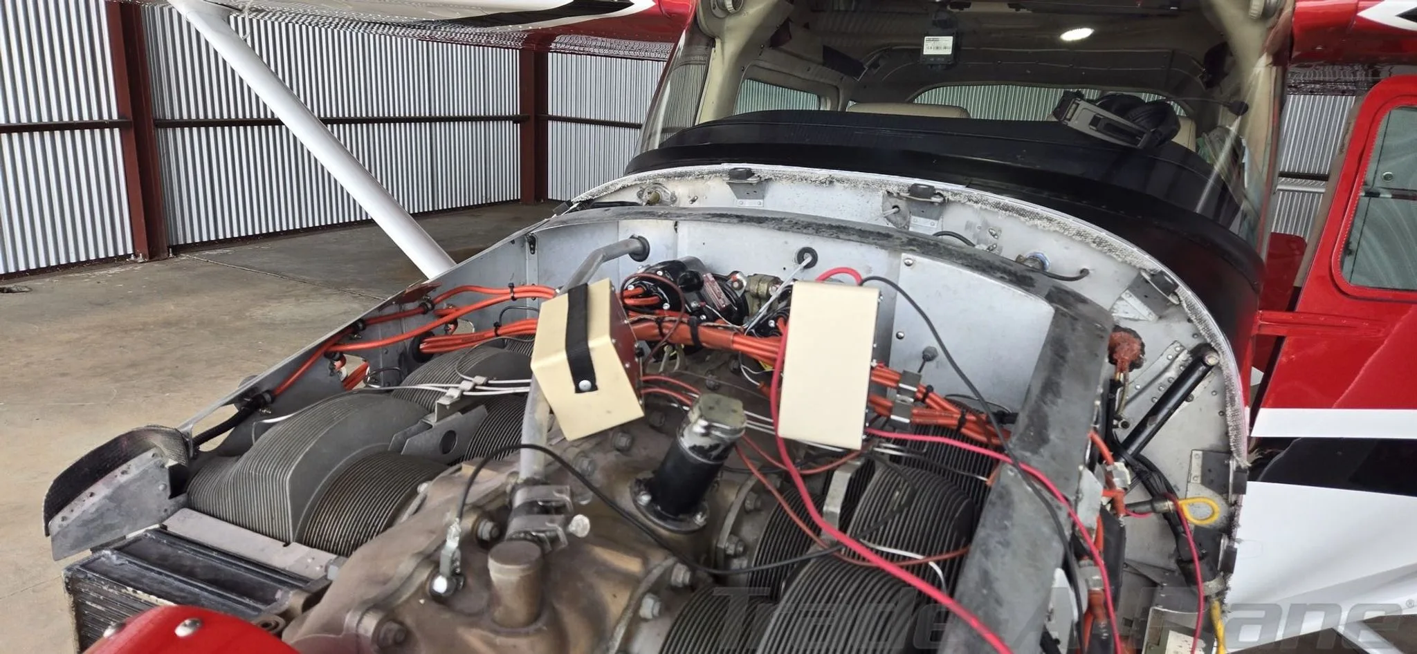 The engine compartment of the aircraft is open, revealing the engine and wiring.