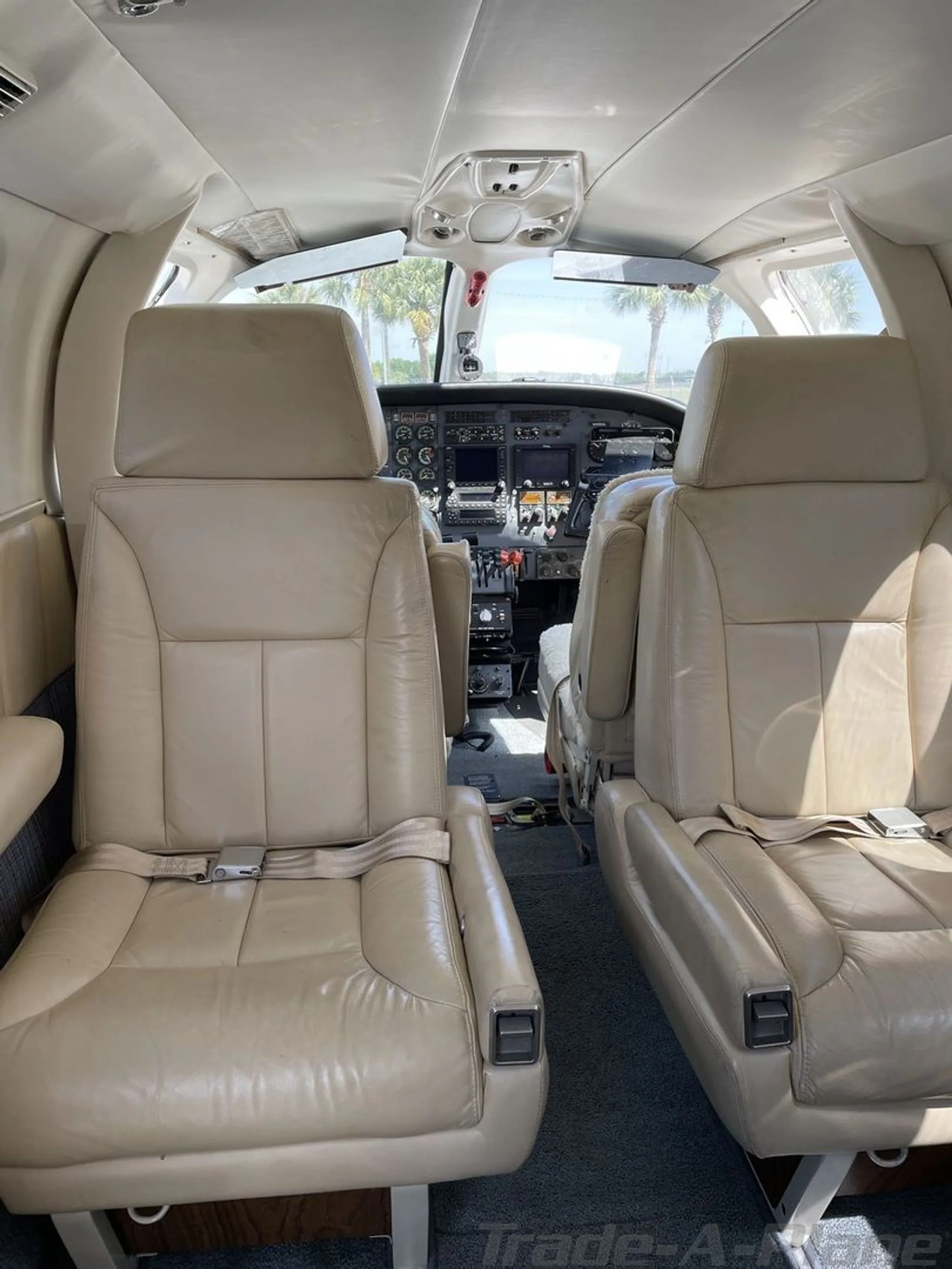 The interior cabin of the aircraft, showing beige leather passenger seats looking towards the cockpit.