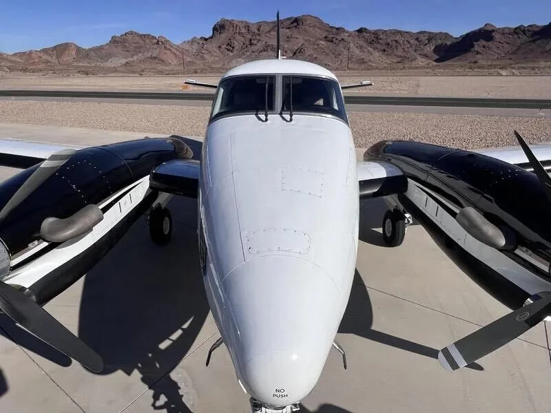 A head-on view of the white and black turboprop aircraft parked on an airfield.