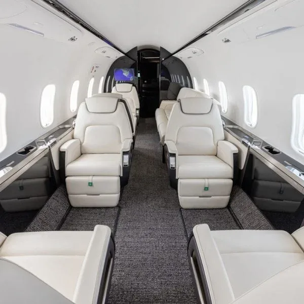 An interior view of a private jet cabin with cream leather seats arranged in a club configuration.