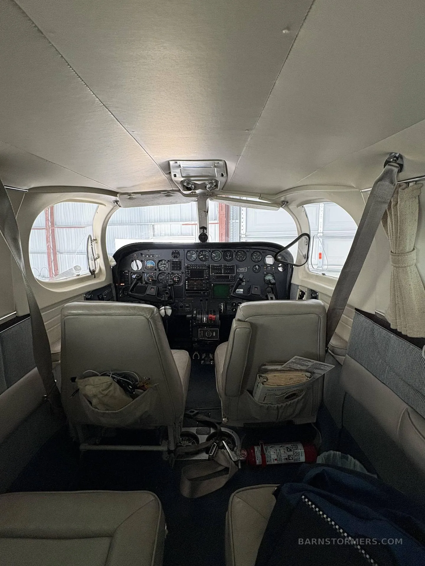 A wide view of the aircraft cockpit, showing the instrument panel, yokes, and two front seats.