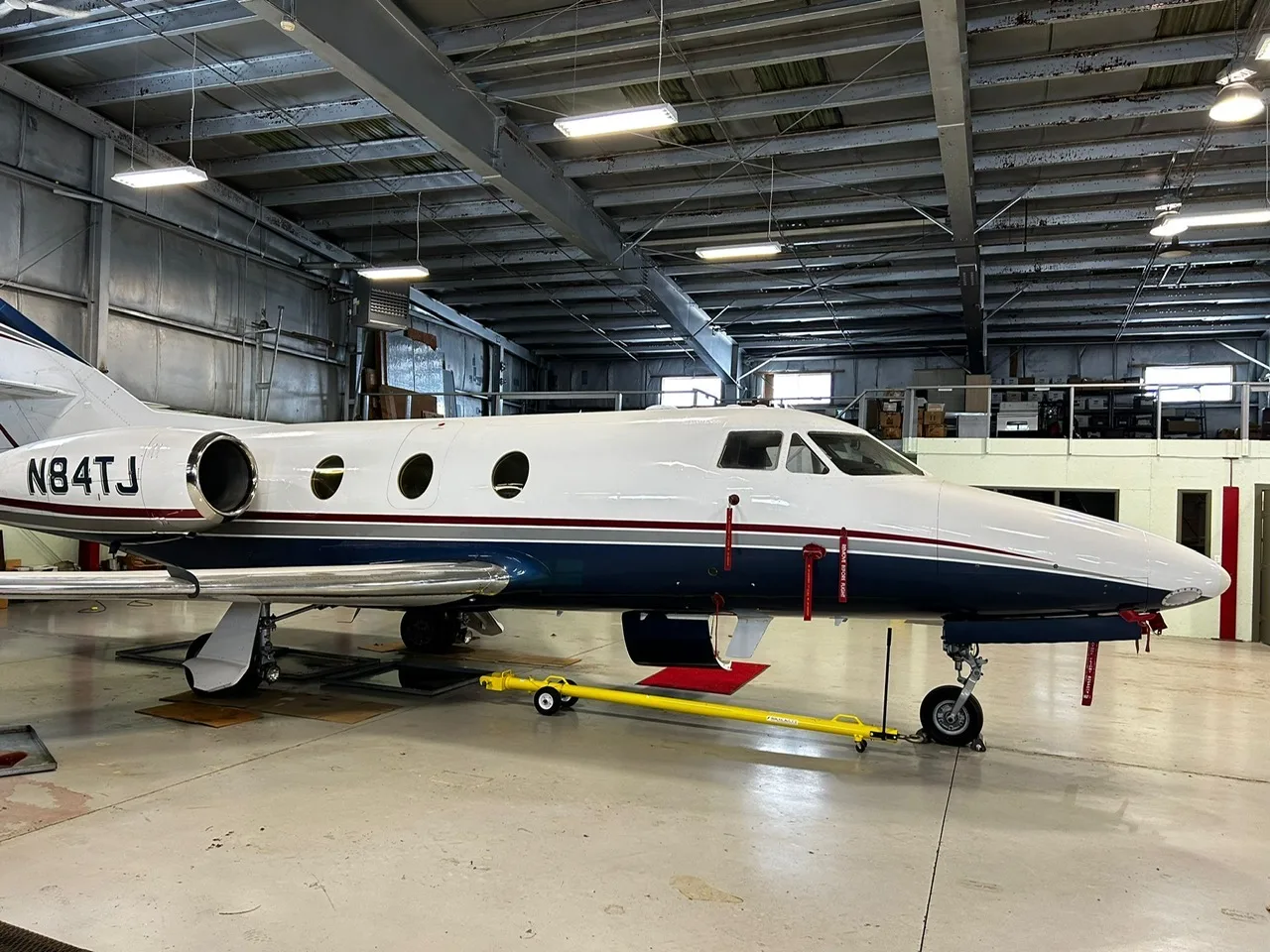 Side view of the aircraft N84TJ in a hangar.