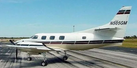 A white twin-engine turboprop aircraft with dark stripes on the fuselage and tail, registration N505GM, on a tarmac under a clear sky.