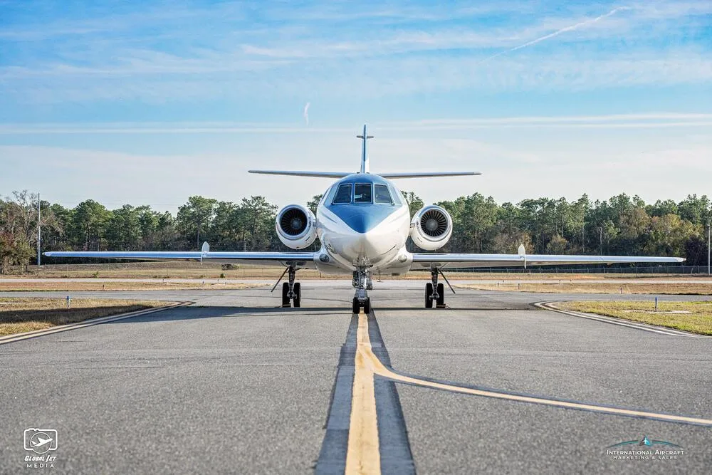 A head-on view of the white and blue business jet N786CM centered on a runway.