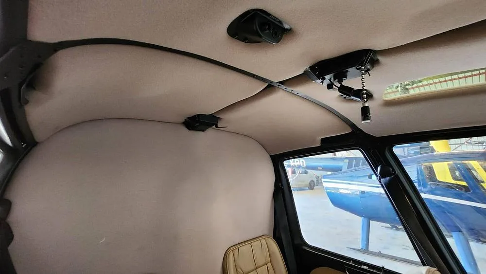 The tan upholstered ceiling and upper interior of a helicopter cabin.