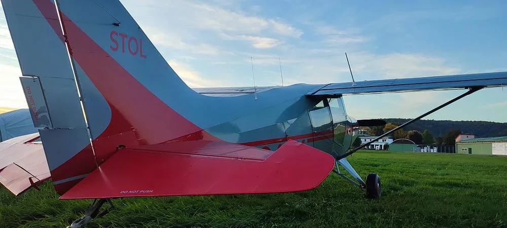 A close-up view of the red and gray tail of the N346X aircraft, with "STOL" visible, parked on grass.
