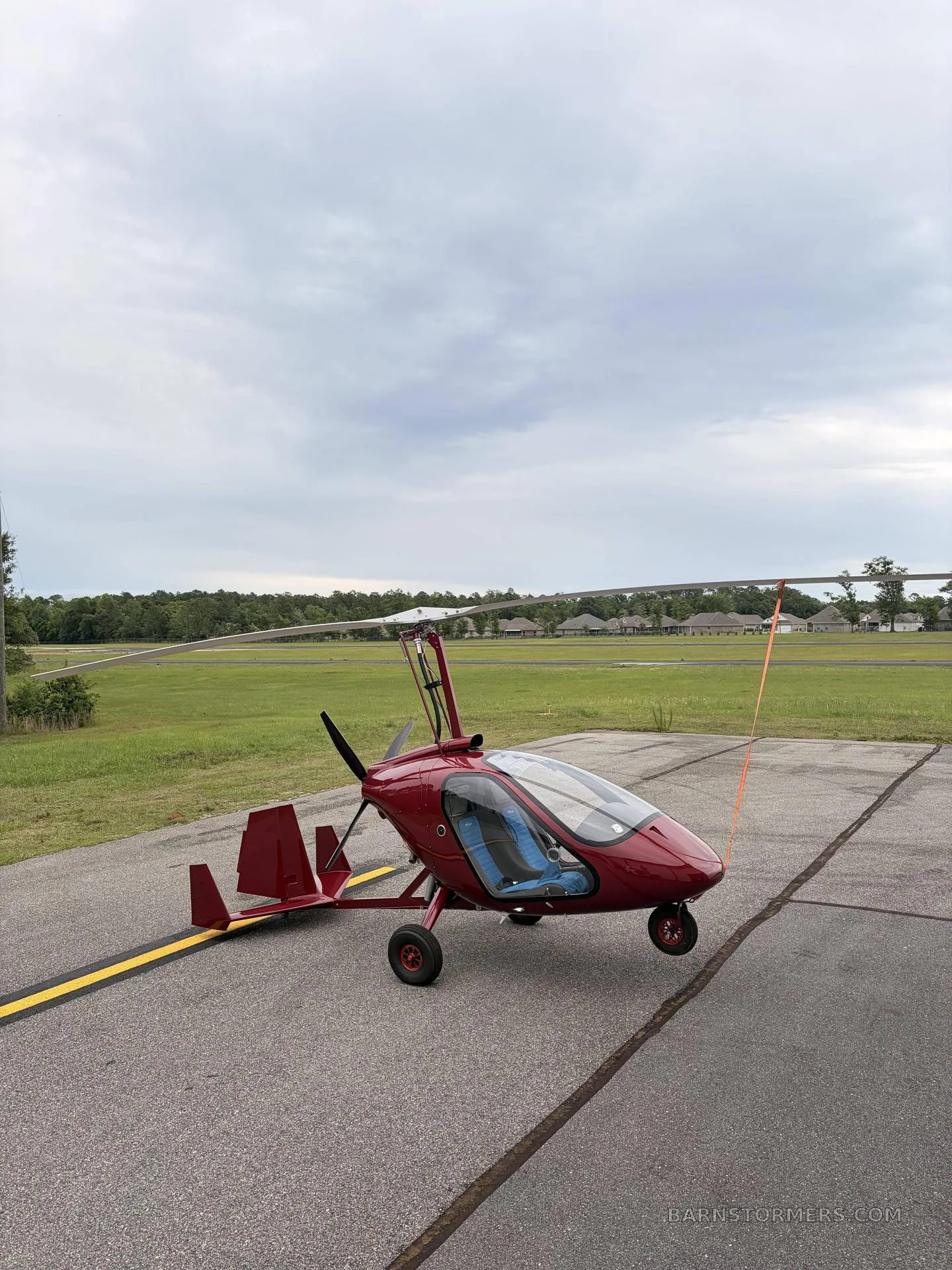 A red MAGNI M24 GYRO parked on the tarmac.