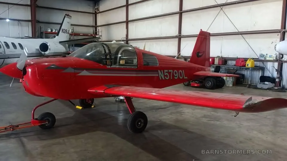 A red Grumman aircraft with registration N5790L is parked in a hangar.