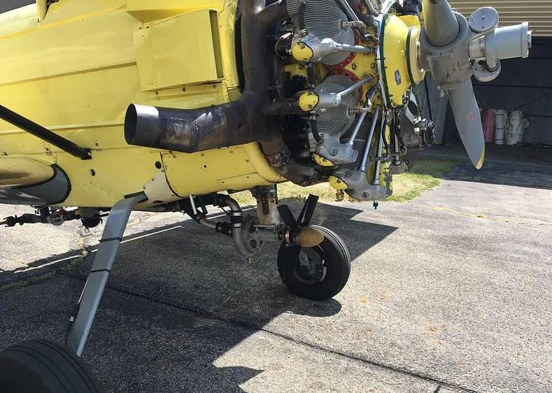 Close-up of the radial engine, propeller, and front landing gear of the yellow biplane.