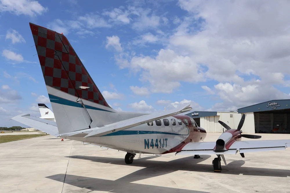 A rear view of the red and silver twin-engine aircraft N441JT, highlighting its distinctive checkered tail.