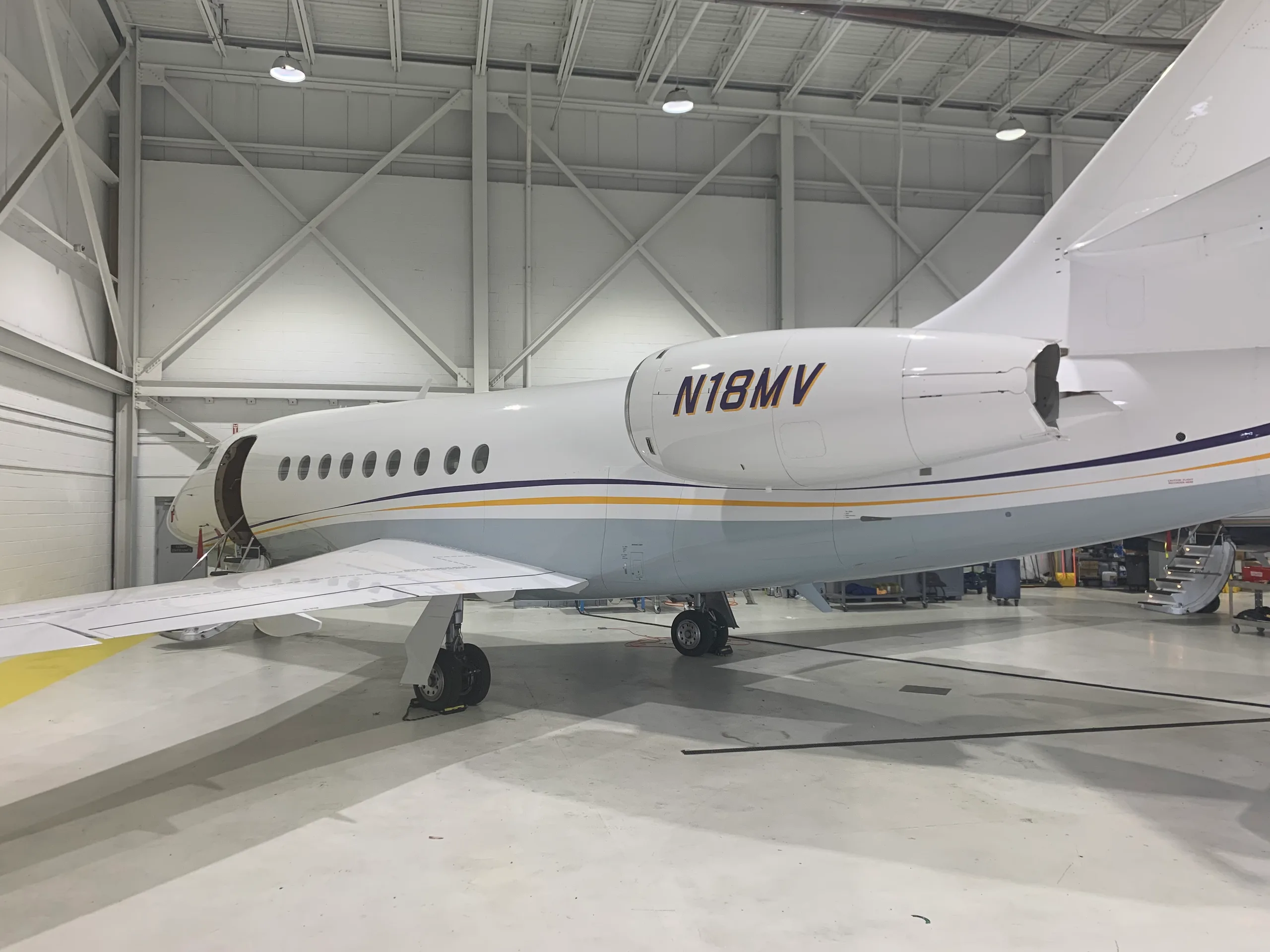 Side view of the aircraft N18MV in a hangar, showing the tail section and open door.