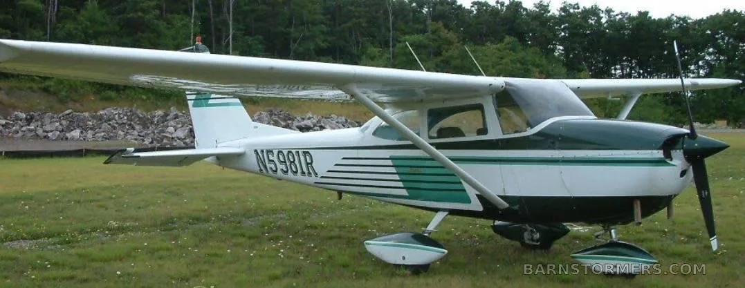 A white and green Cessna N5981R on a grassy field, viewed from the front right.
