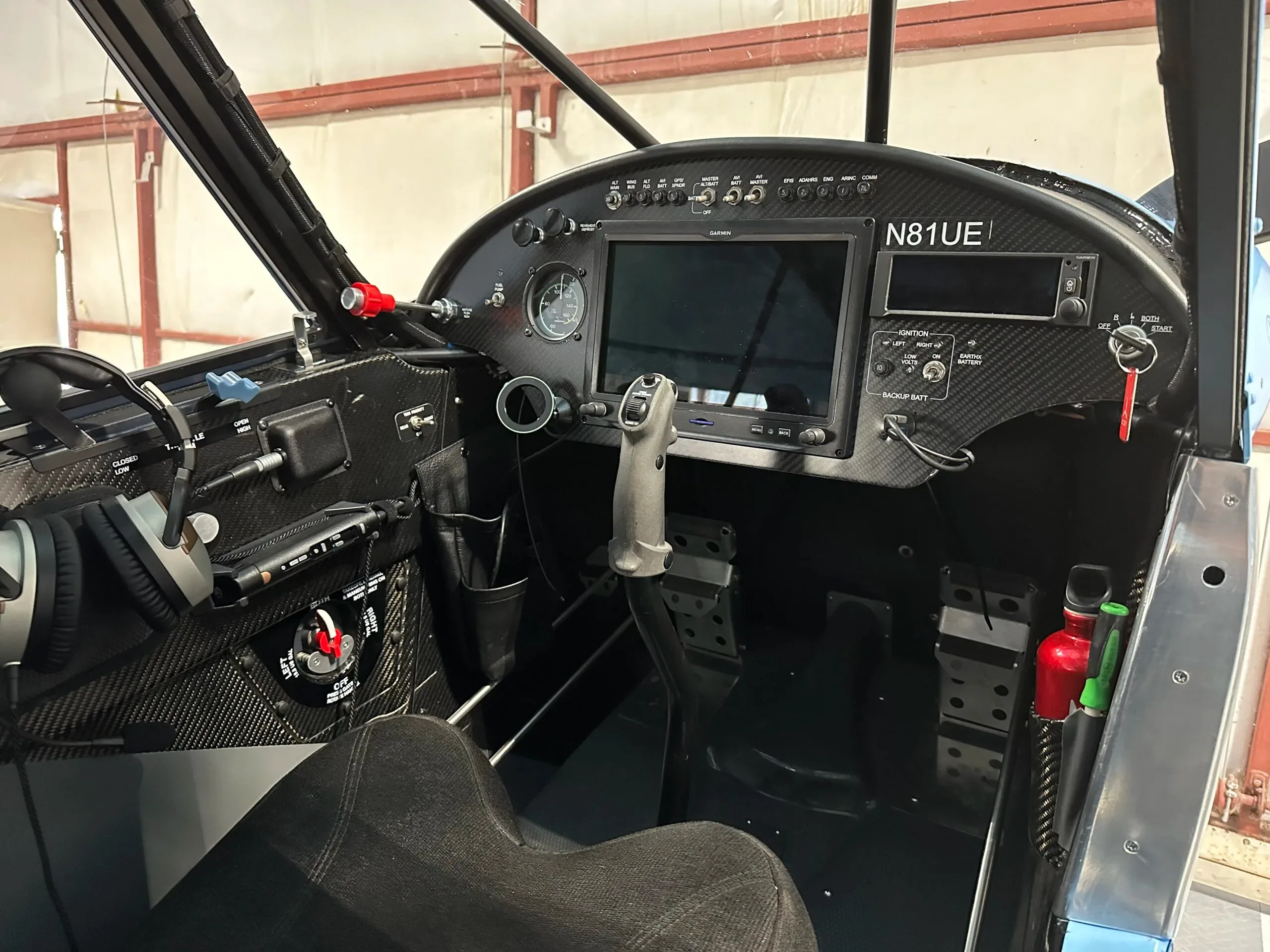 The cockpit of the aircraft, featuring a modern glass panel display, a joystick control, and carbon fiber trim.