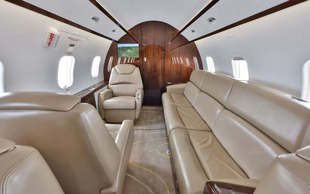 The rear section of the aircraft cabin features a long tan leather sofa and a single executive seat.