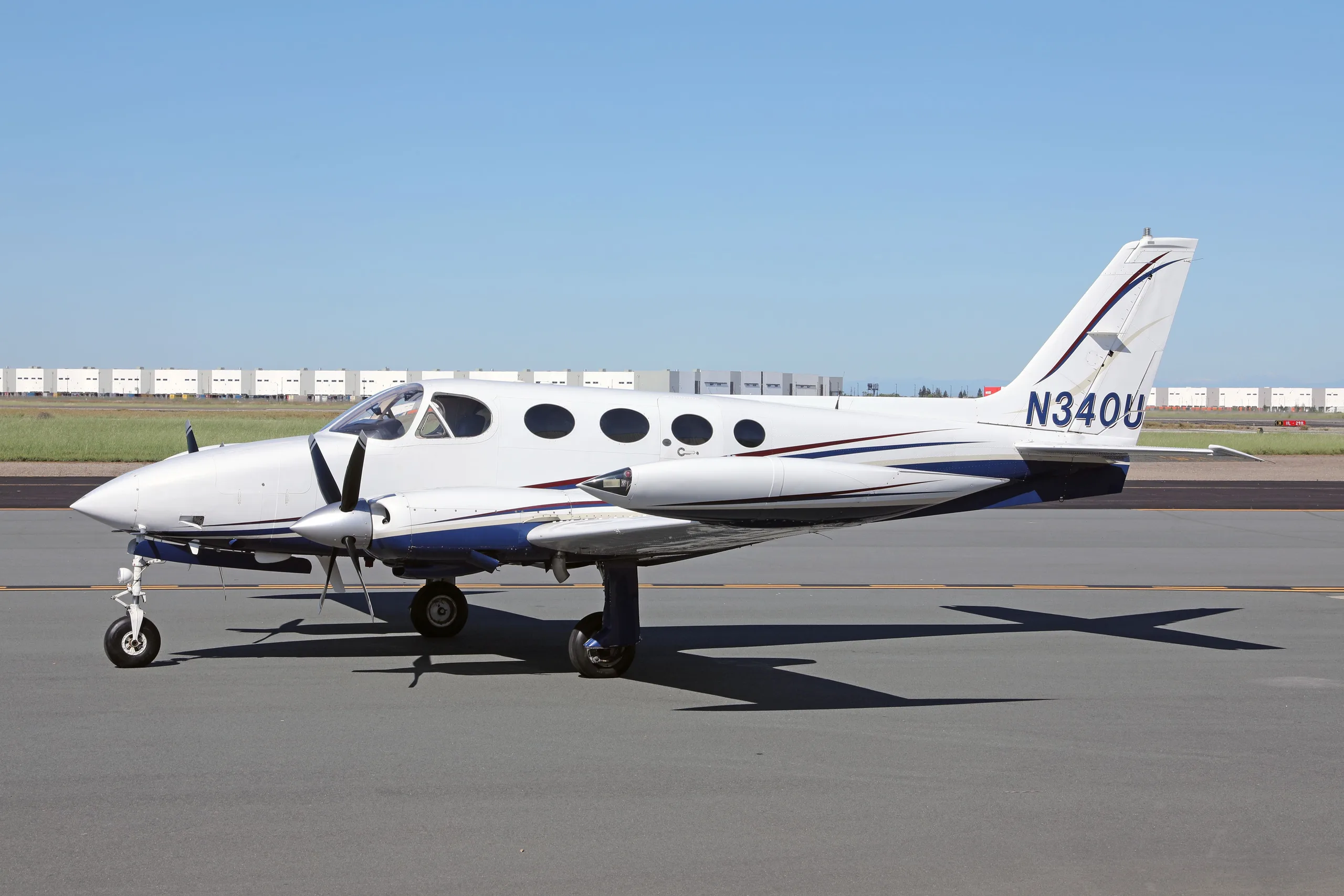 A white and blue Cessna 340 twin-engine aircraft with registration N340U parked on an airfield.