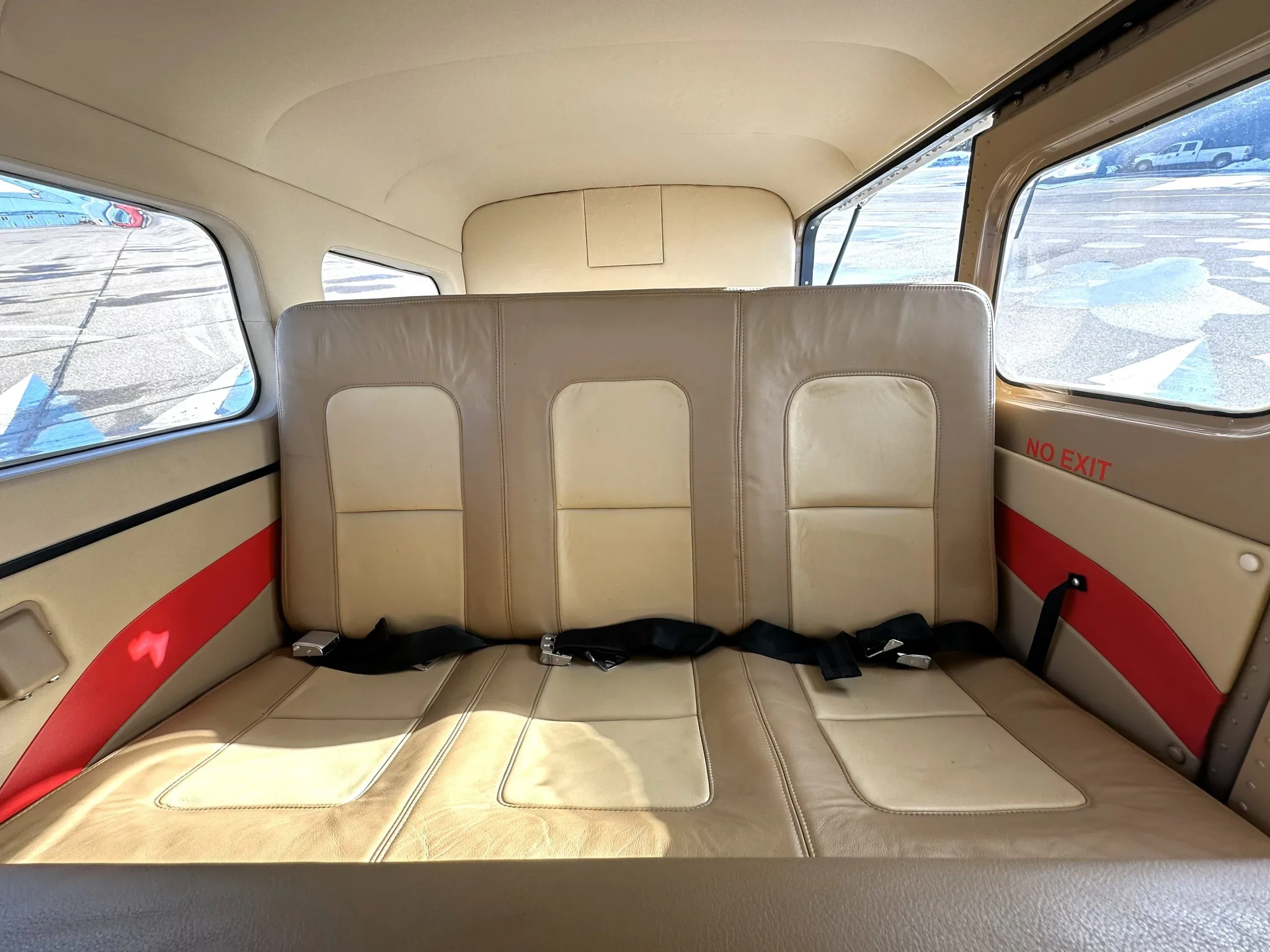 Straight-on view of the tan leather rear bench seat inside the aircraft cabin.