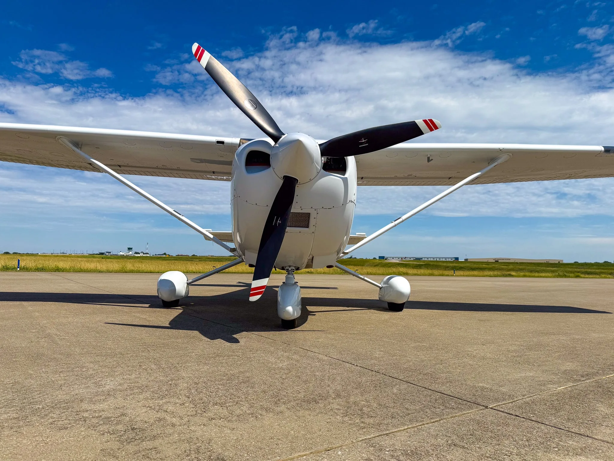 Front view of a white Cessna 182 Skylane with red and gray stripes, registration N624CF, parked on an asphalt ramp.