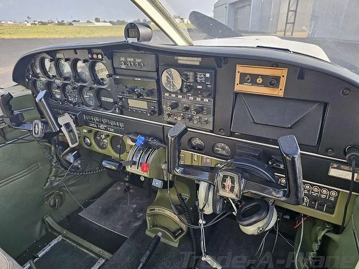 The cockpit of the Piper Cherokee 180, featuring a green instrument panel and dual yokes.