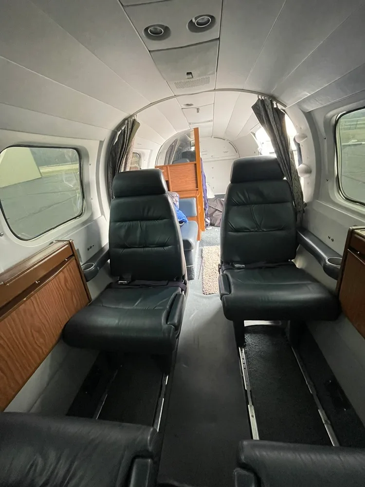 The aircraft cabin interior with dark leather seats and wood paneling, looking towards the rear of the cabin.