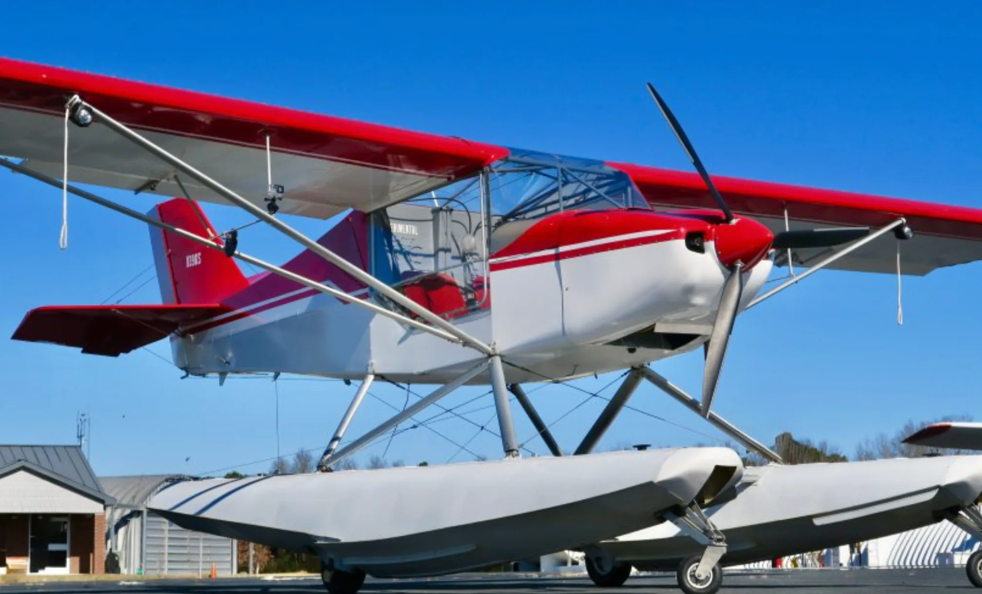 A red and white N39KS floatplane with its propeller and floats visible, parked on an airfield.