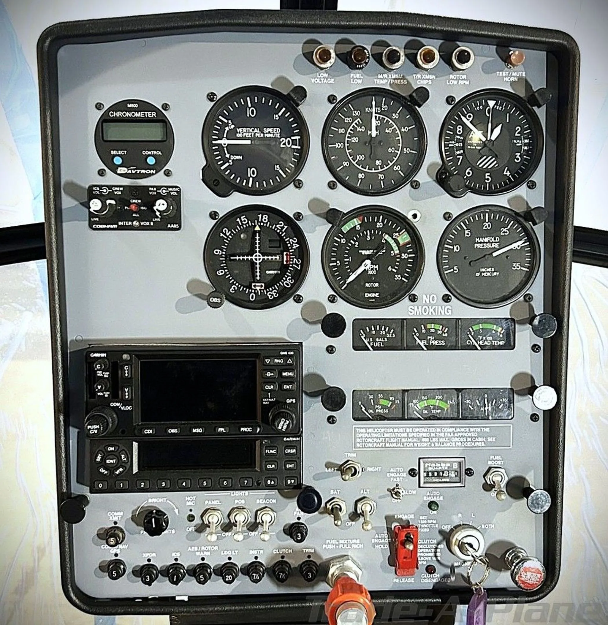 The instrument panel of a Schweizer S300CBi helicopter features analog gauges, a digital chronometer, and a Garmin GPS/radio unit.