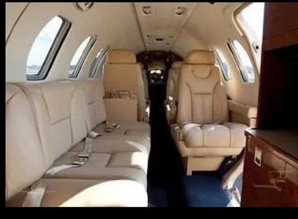 The aircraft's interior cabin with beige leather seating, including a side couch and individual seats.