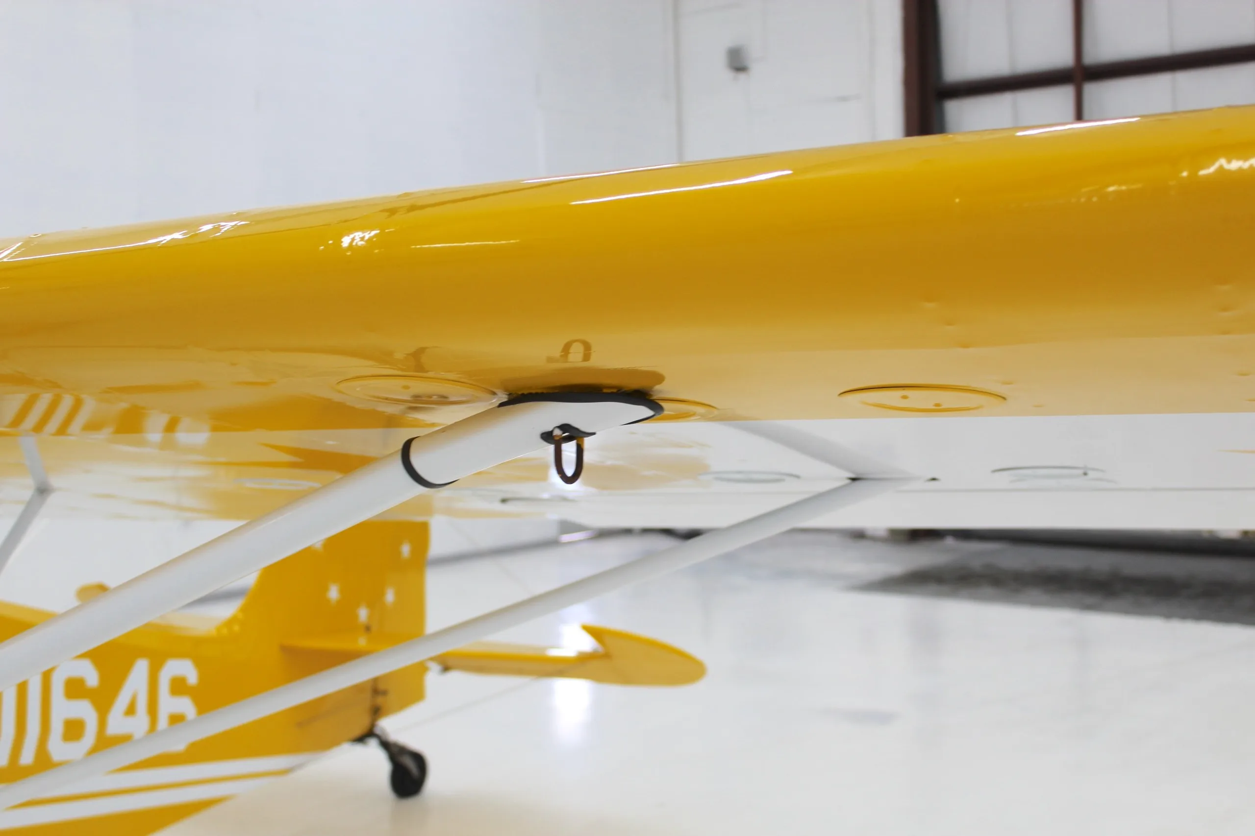 A close-up view of the white wing strut attachment point on the underside of the yellow wing of N11646.