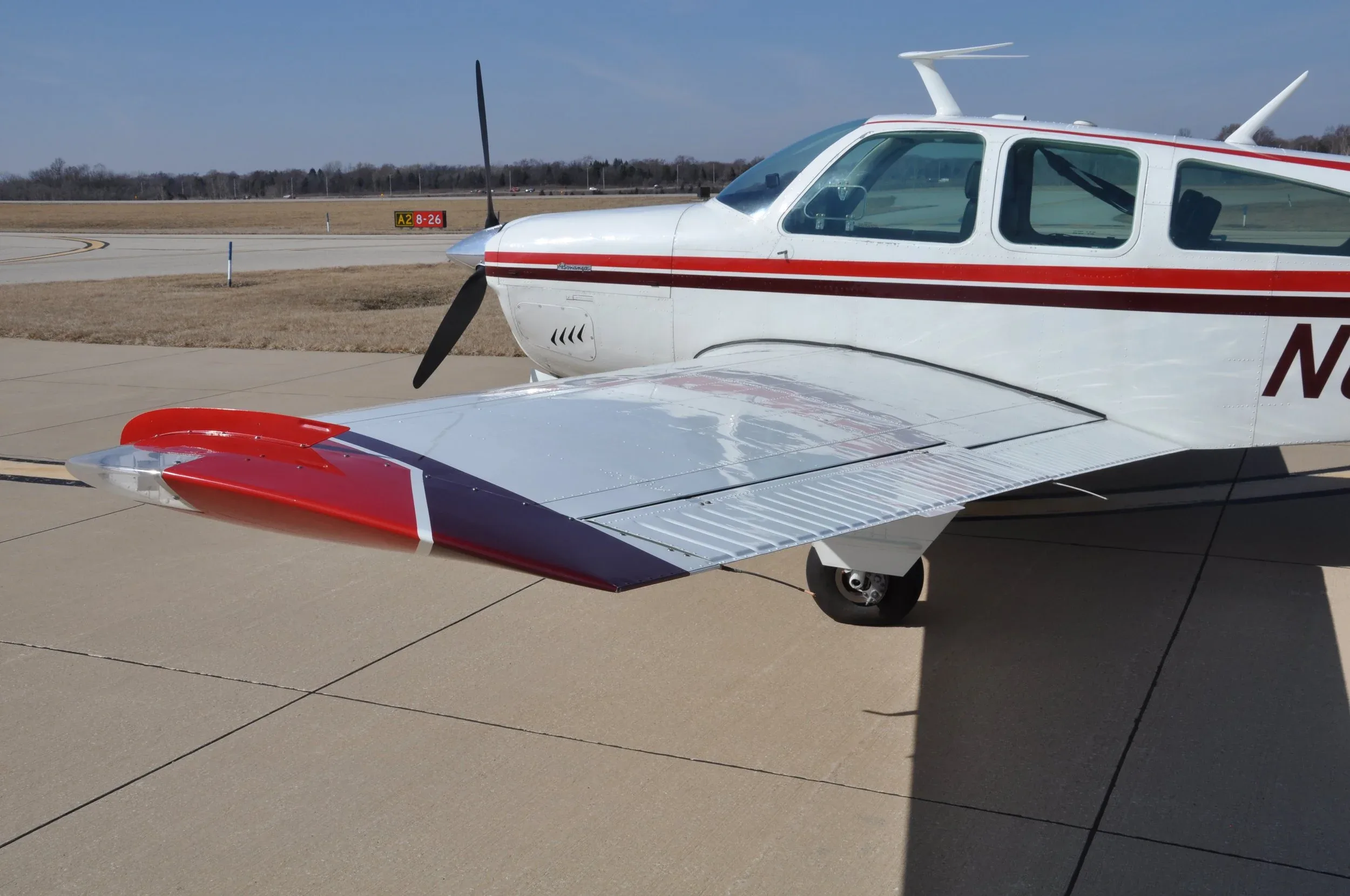 A front-side view of the white aircraft N6089S, showing the propeller and the right wing with red and purple accents.