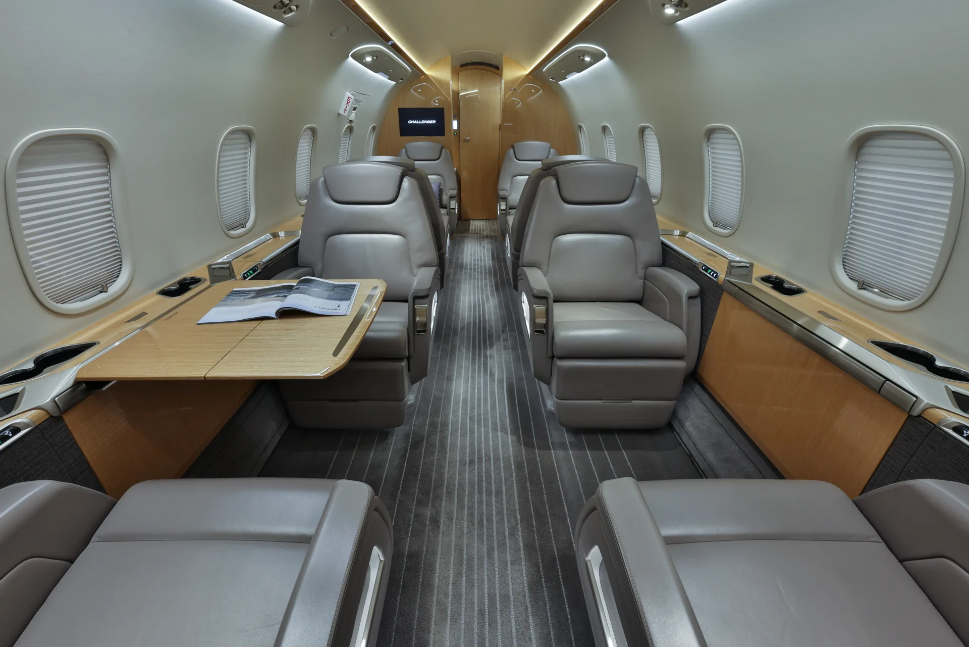 The interior of a Challenger aircraft with leather seats and a table.