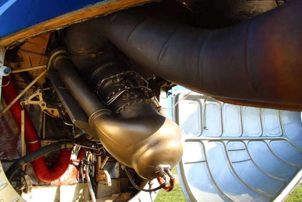 An open engine compartment of a helicopter reveals the exhaust system and internal components.