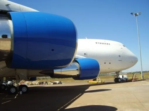 A close-up view of two blue engines and the front fuselage of a white Boeing 747 on an airfield.