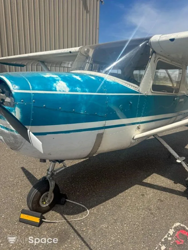 Side view of the front fuselage of a Cessna 150 with a weathered blue and white paint scheme.