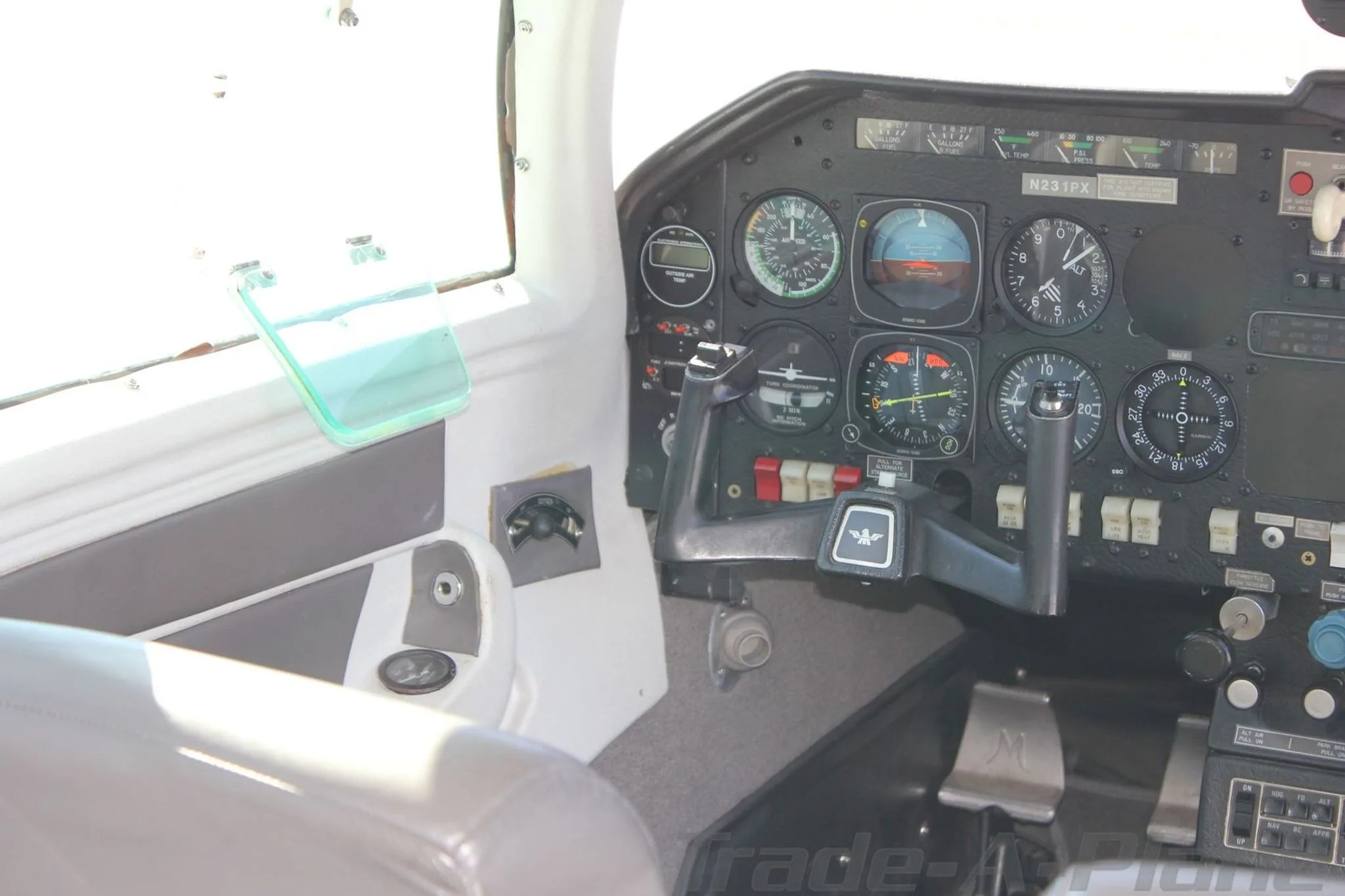 View of the aircraft cockpit from the passenger seat, showing the instrument panel and controls.