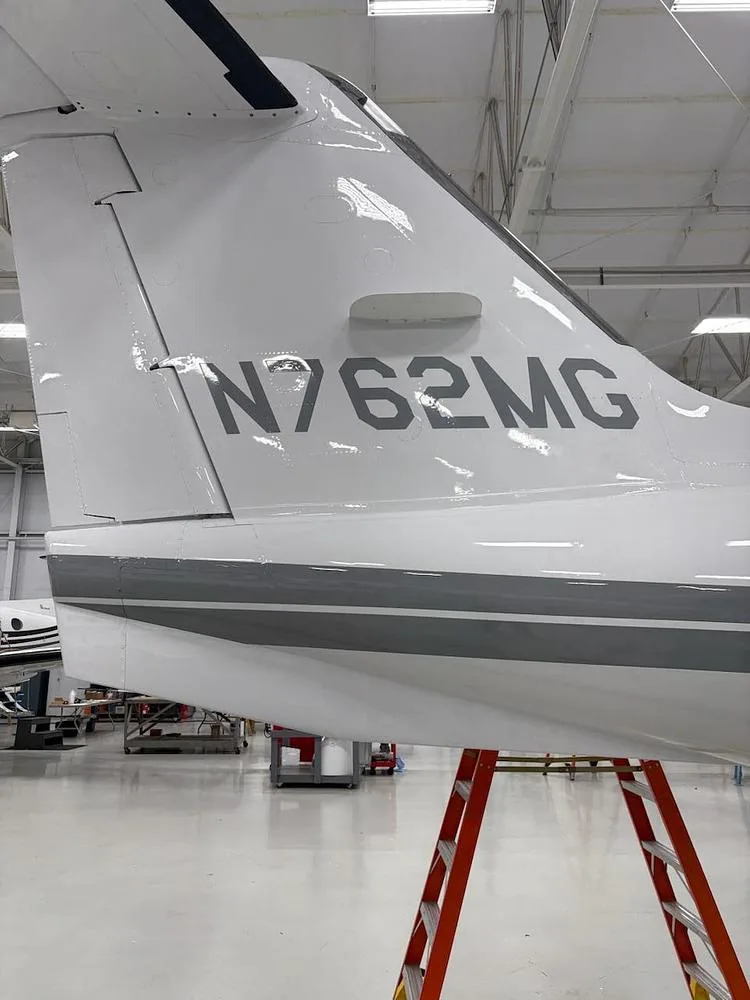 A close-up view of the white tail of a Learjet, showing the registration N762MG and a grey stripe.