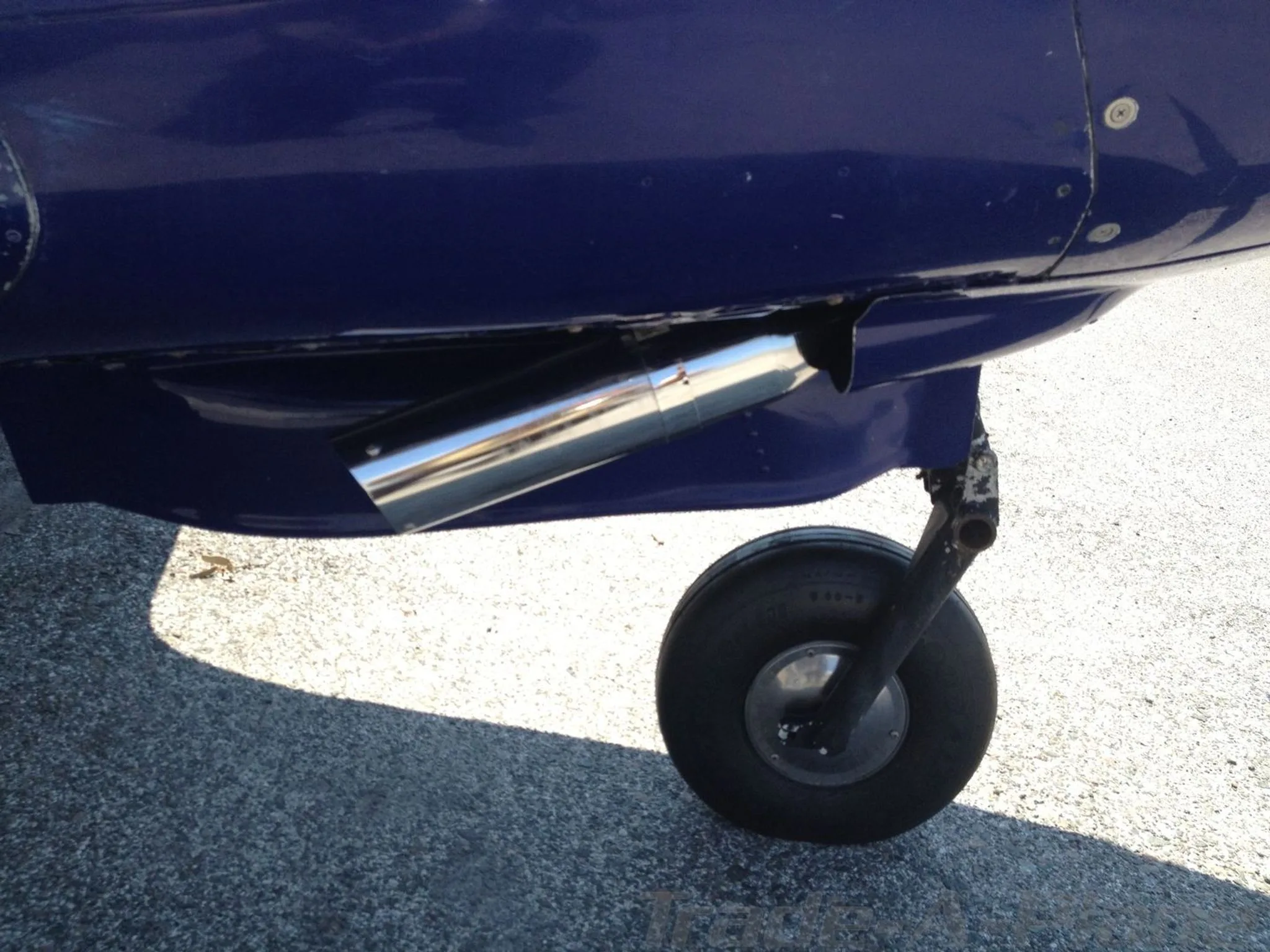 Close-up of the aircraft's exhaust pipe and nose landing gear.