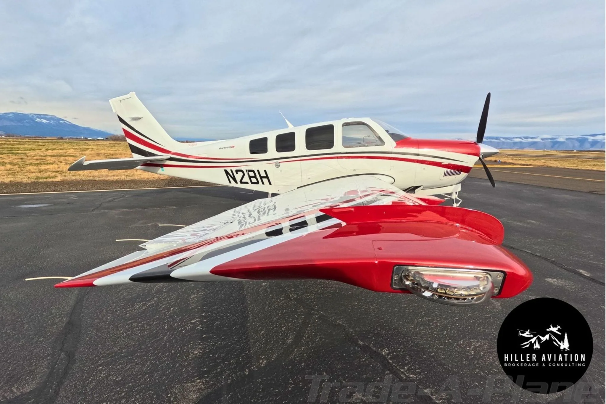 Side view of a white and red Beechcraft Bonanza G36 (N2BH) with its wing in the foreground.