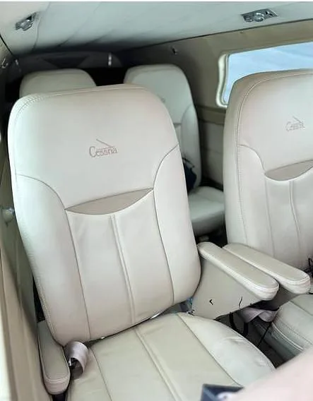 Light-colored leather passenger seats with "Cessna" embossed, viewed inside the aircraft cabin.