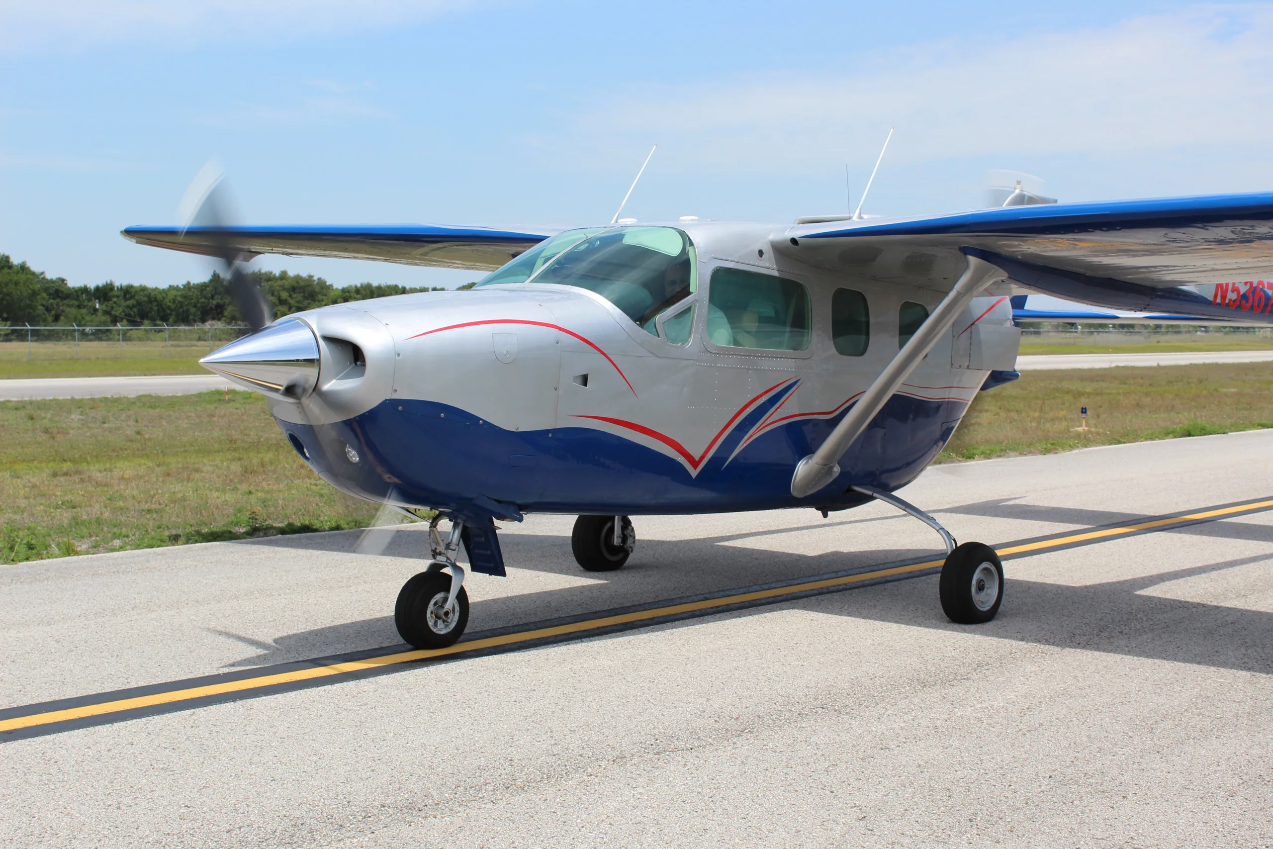A silver and blue single-engine propeller aircraft, registration N5367, with its propeller spinning on an airfield tarmac.