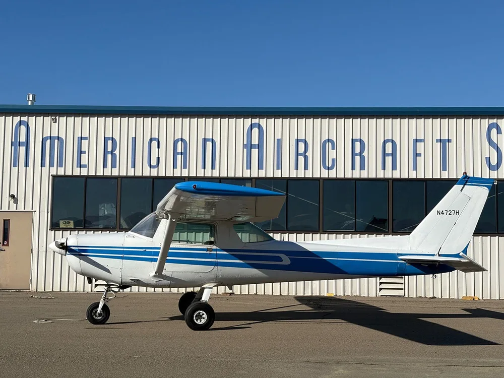 A side view of a white and blue Cessna 172 aircraft (N4727H) parked on an airfield.
