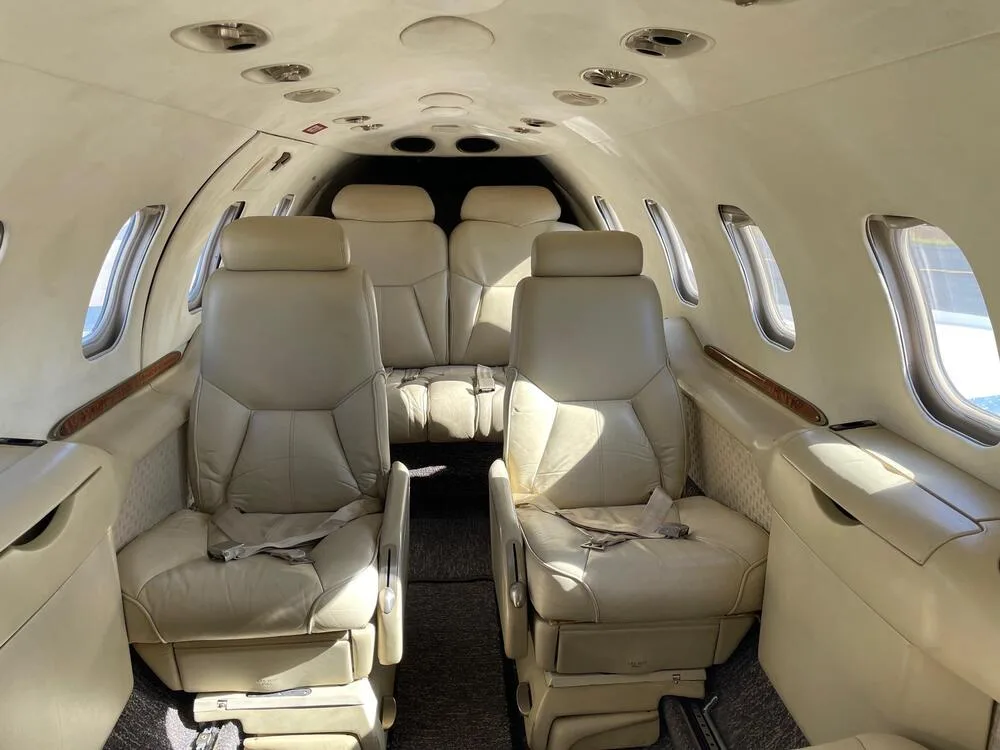 The aircraft's cabin interior with light beige leather seats arranged in a club configuration.