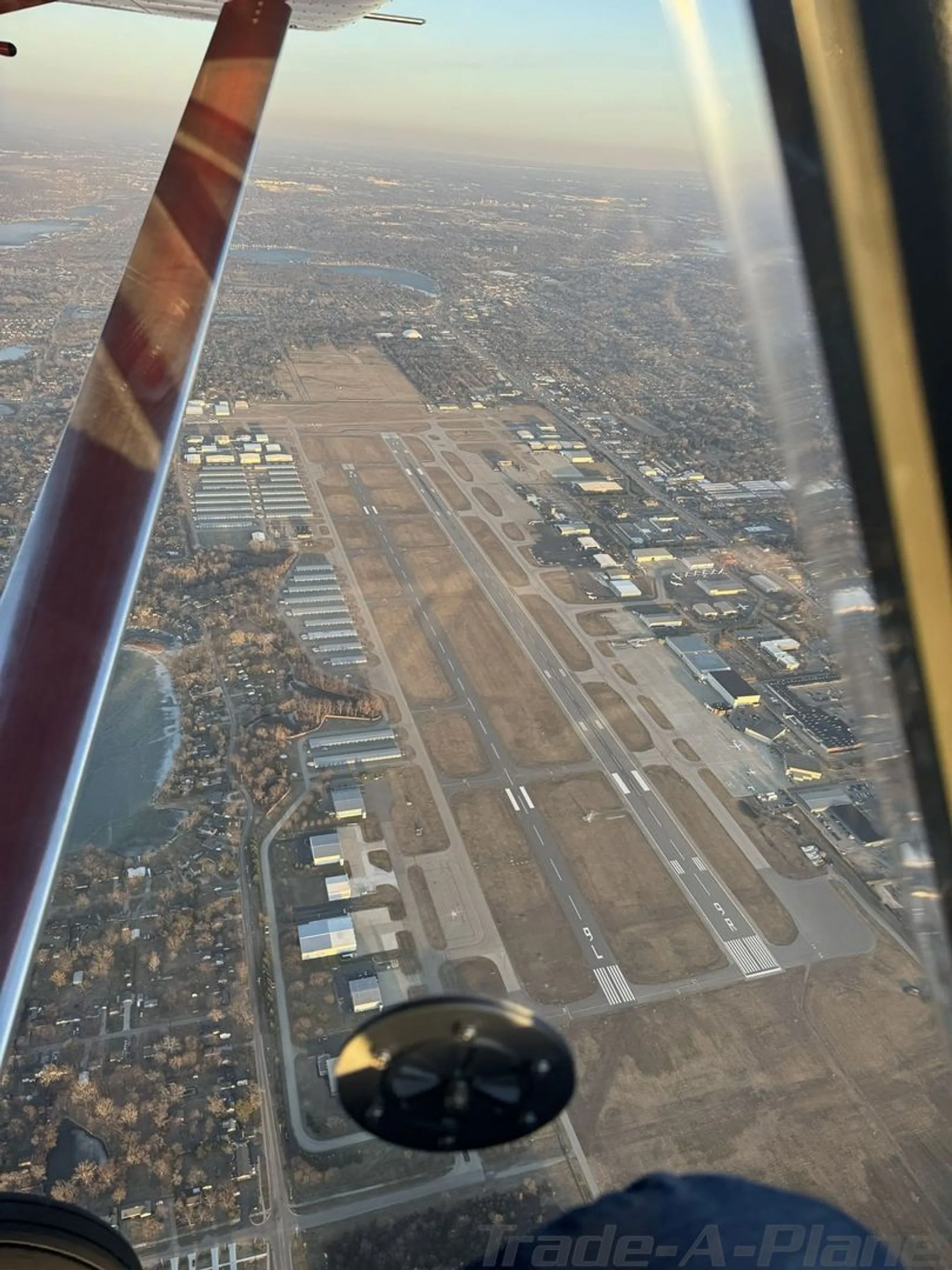 Aerial view of a large airport with multiple runways and surrounding urban landscape, seen from an aircraft wing.