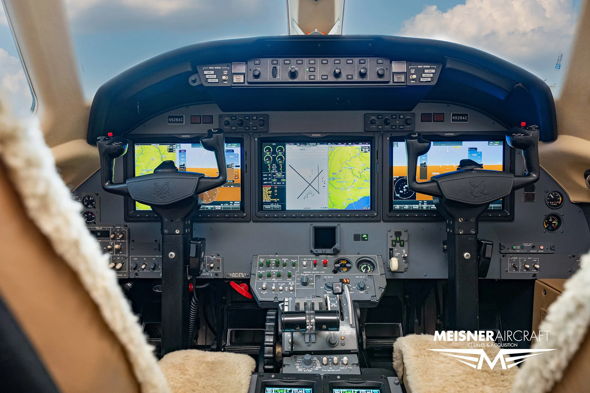 The cockpit of a business jet with multiple digital displays showing flight information and maps, with a 'Meisner Aircraft' logo.