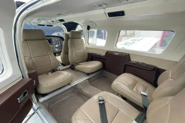 The beige leather interior cabin of a small aircraft with multiple passenger seats.