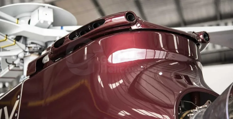 A close-up view of the top of a burgundy helicopter's fuselage and rotor mast.